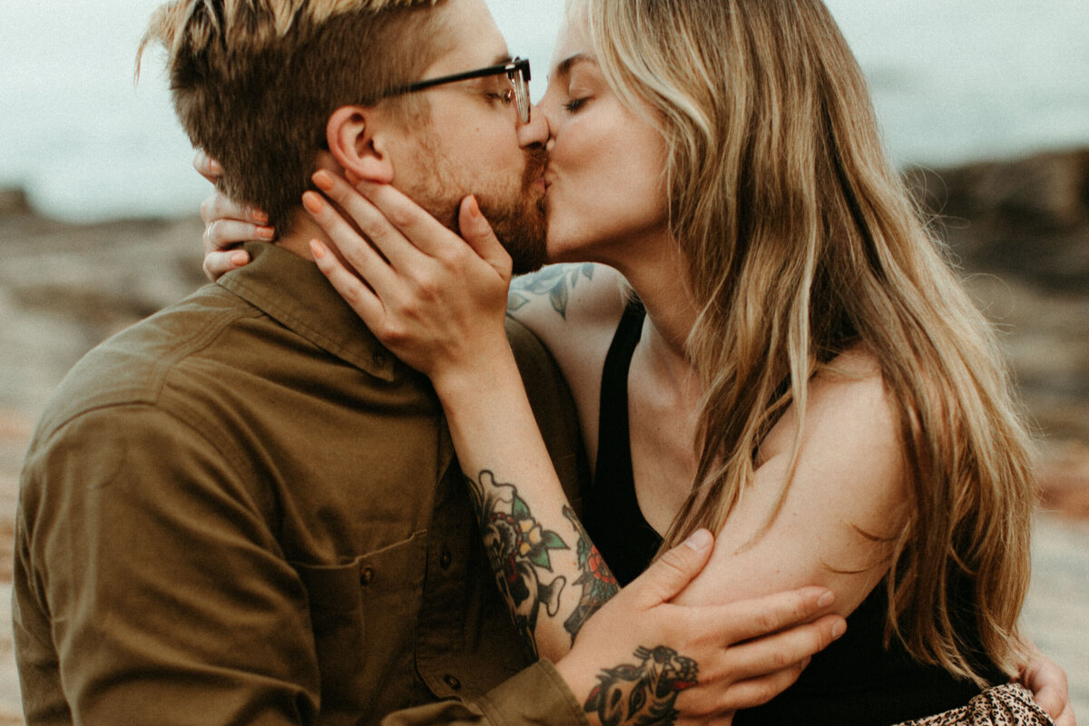 Couple with tattoos holding each other and kissing
