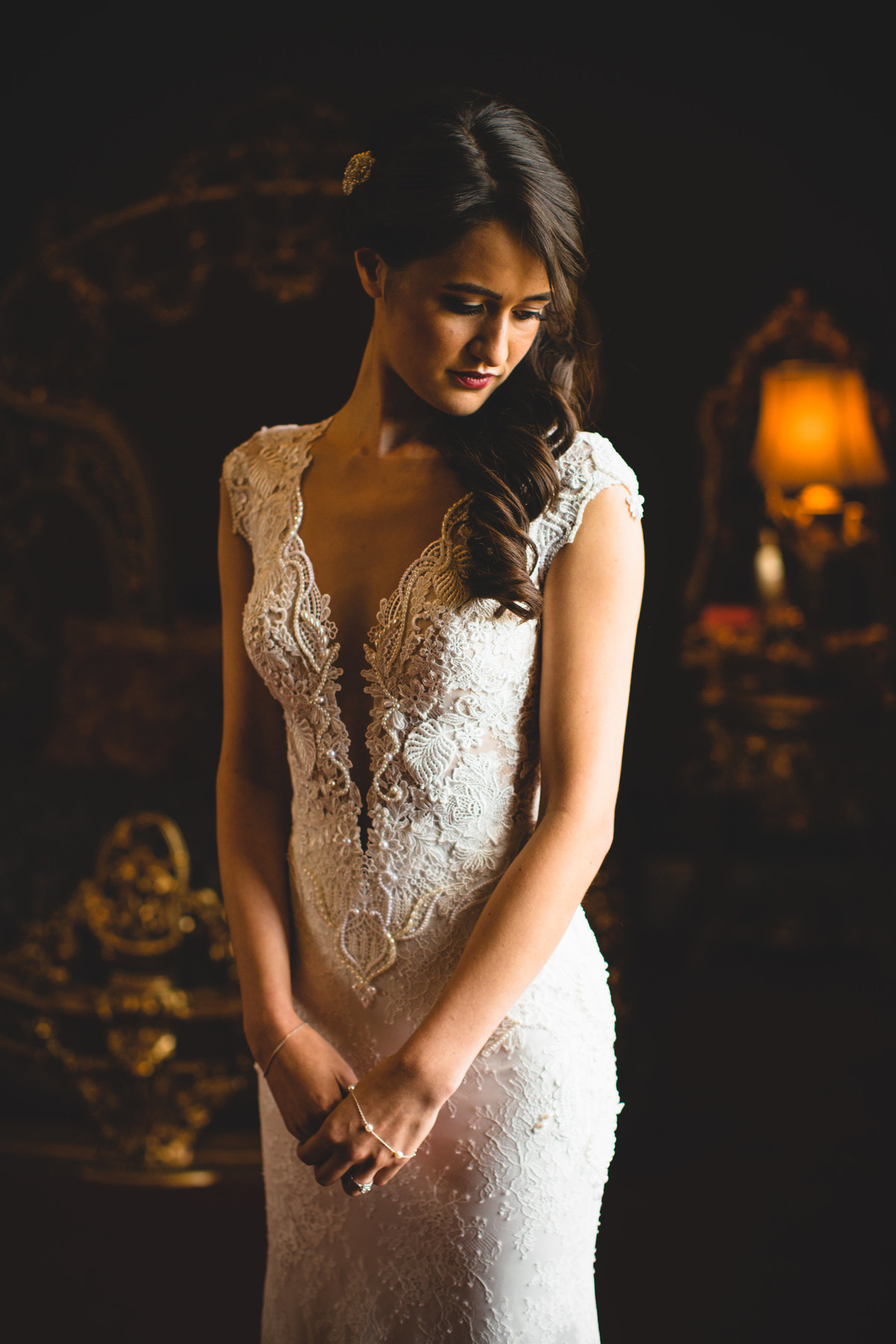 A beautiful bride stood by a window at Knowsley hall in light