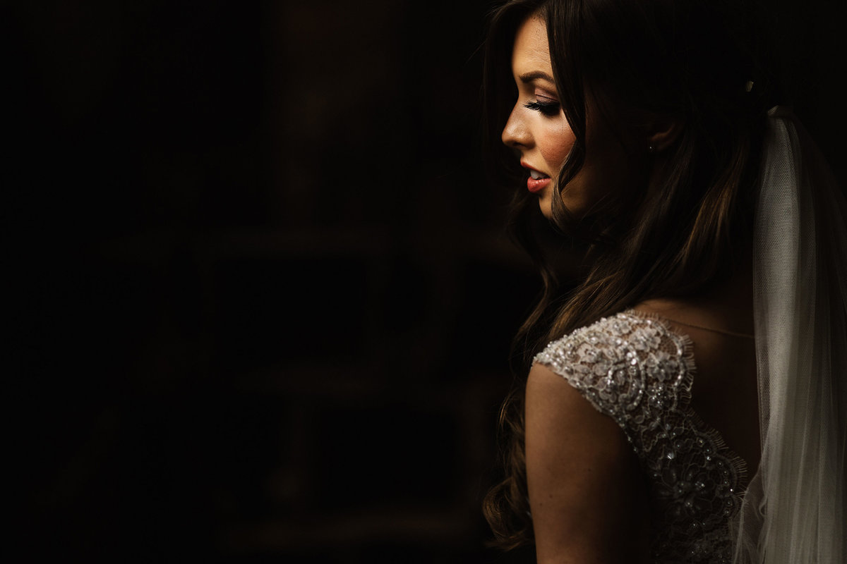 Brides face highlighted by natural light in a dark room