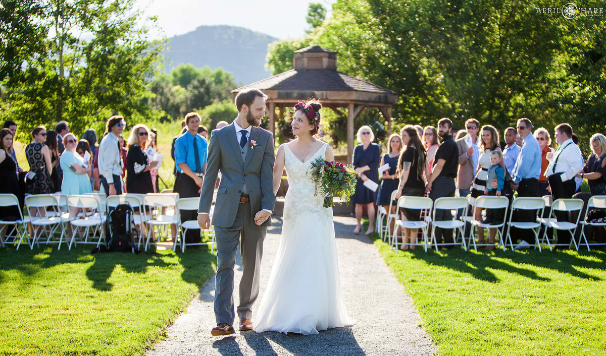 Bride and groom walk out together from their Chatfield Farms Wedding Ceremony in Colorado