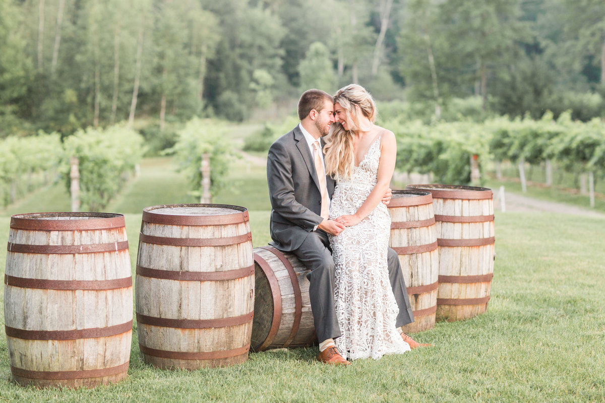 Bride and groom sitting on wine barrels at winery