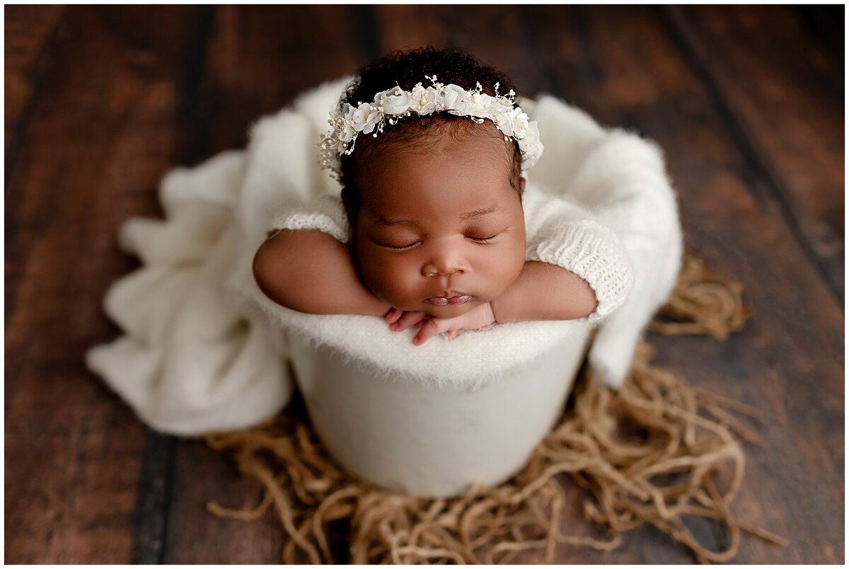 A picture-perfect pose: A portrait of a newborn baby in a prop bucket, captured from a flattering angle, showcasing their adorable position and the artistry of the photography session.