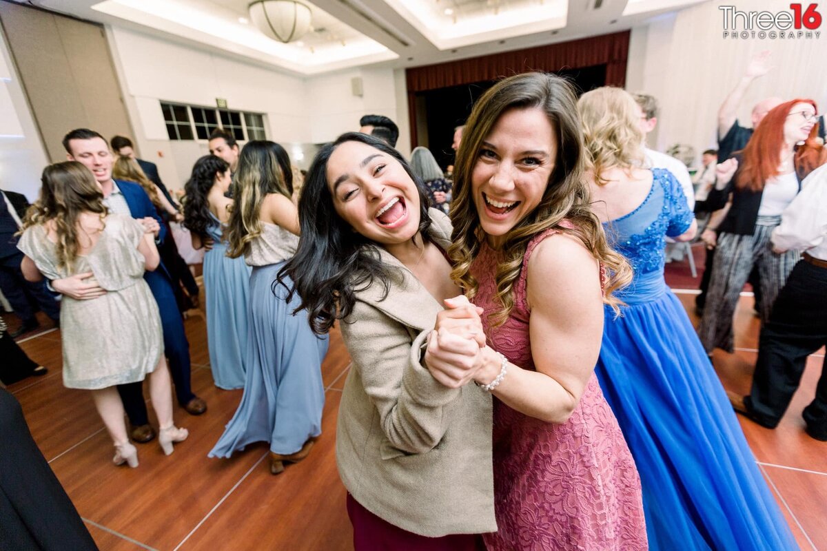 Ladies dance together and smile for the camera during a wedding reception