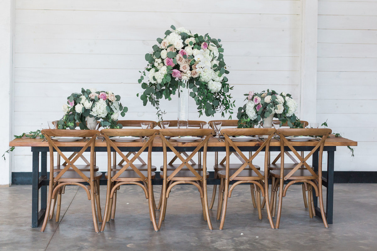 Tall garden centerpiece with wooden table and crossback chairs