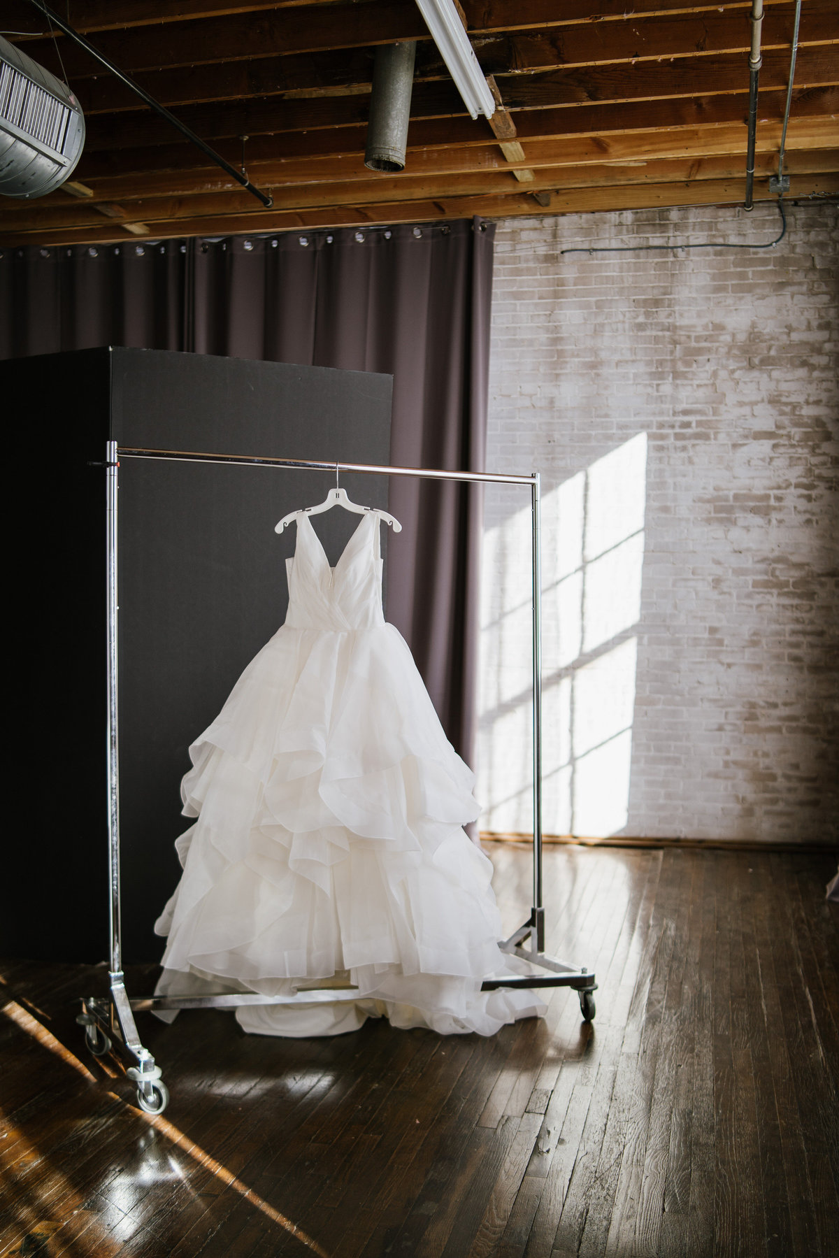 Bridal gown hanging on clothes rack in studio while bride gets ready in down town san antonio