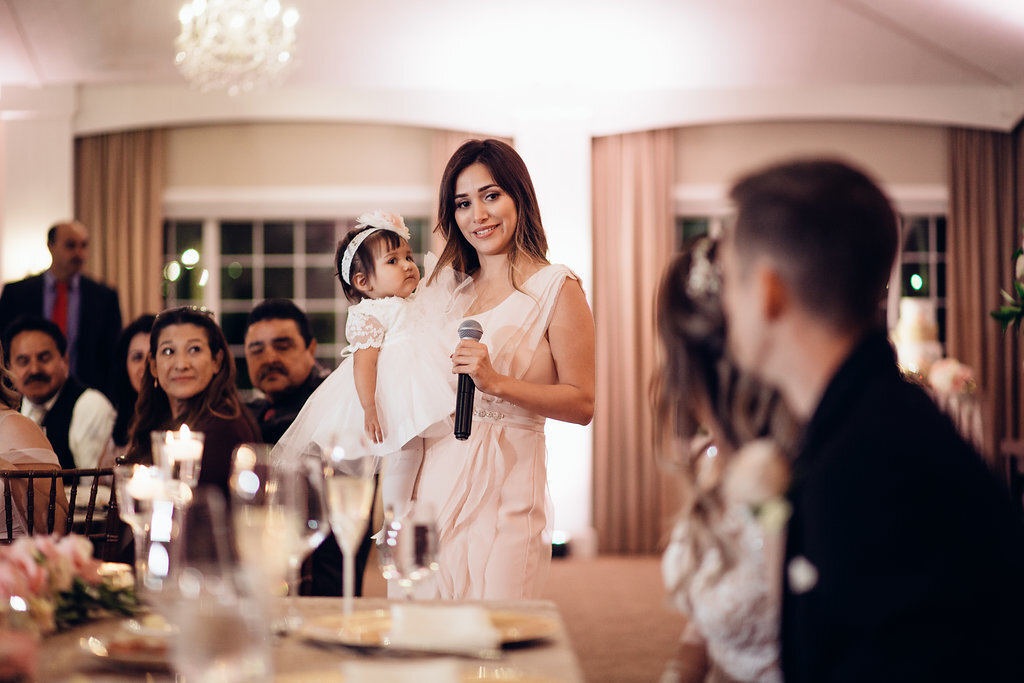 Wedding Photograph Of Woman Speaking In a Microphone While Looking at Bride And Groom Los Angeles