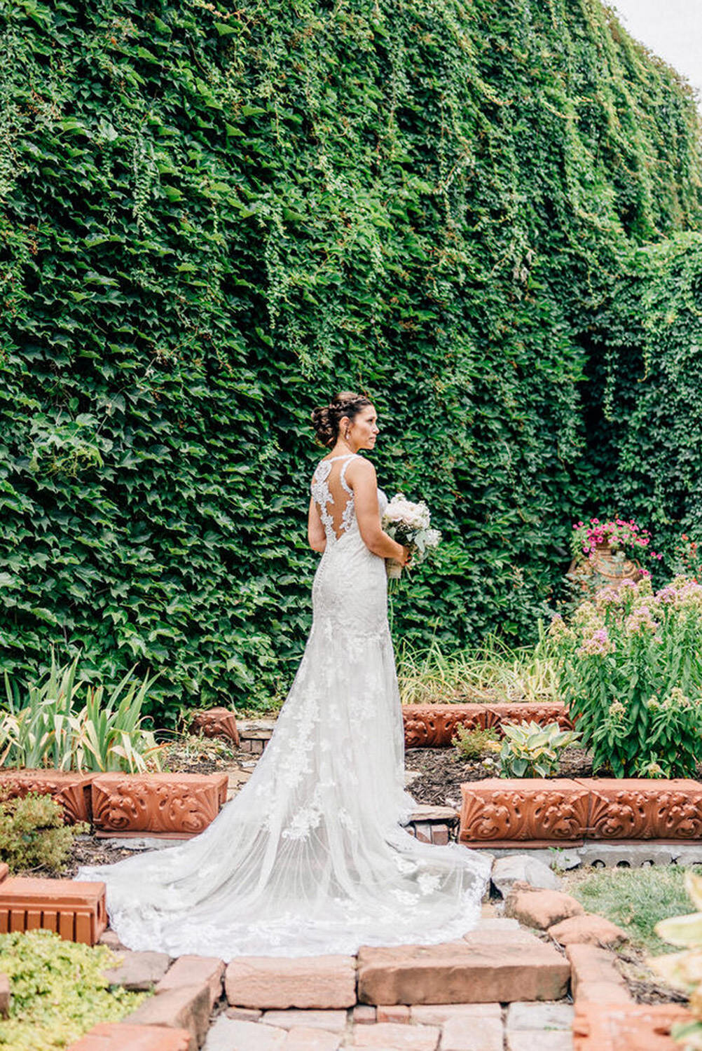 Beautiful bride poses in front of ivy wall in omaha