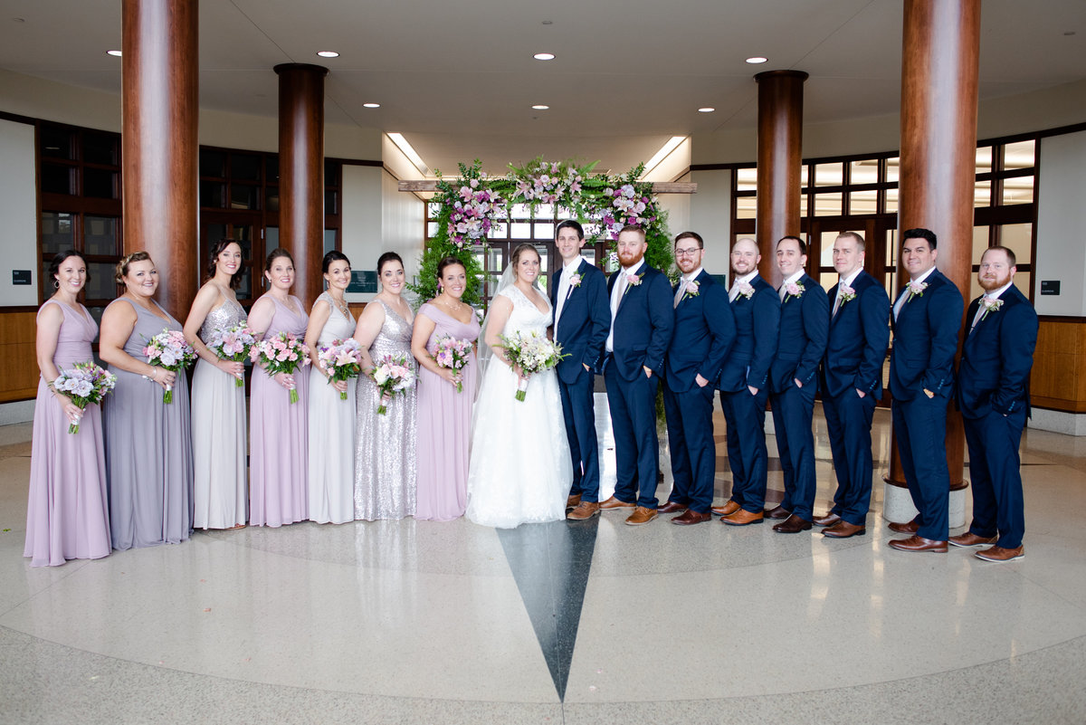 A group photo of the bridesmaids and the groomsmen surrounding a wife and husband