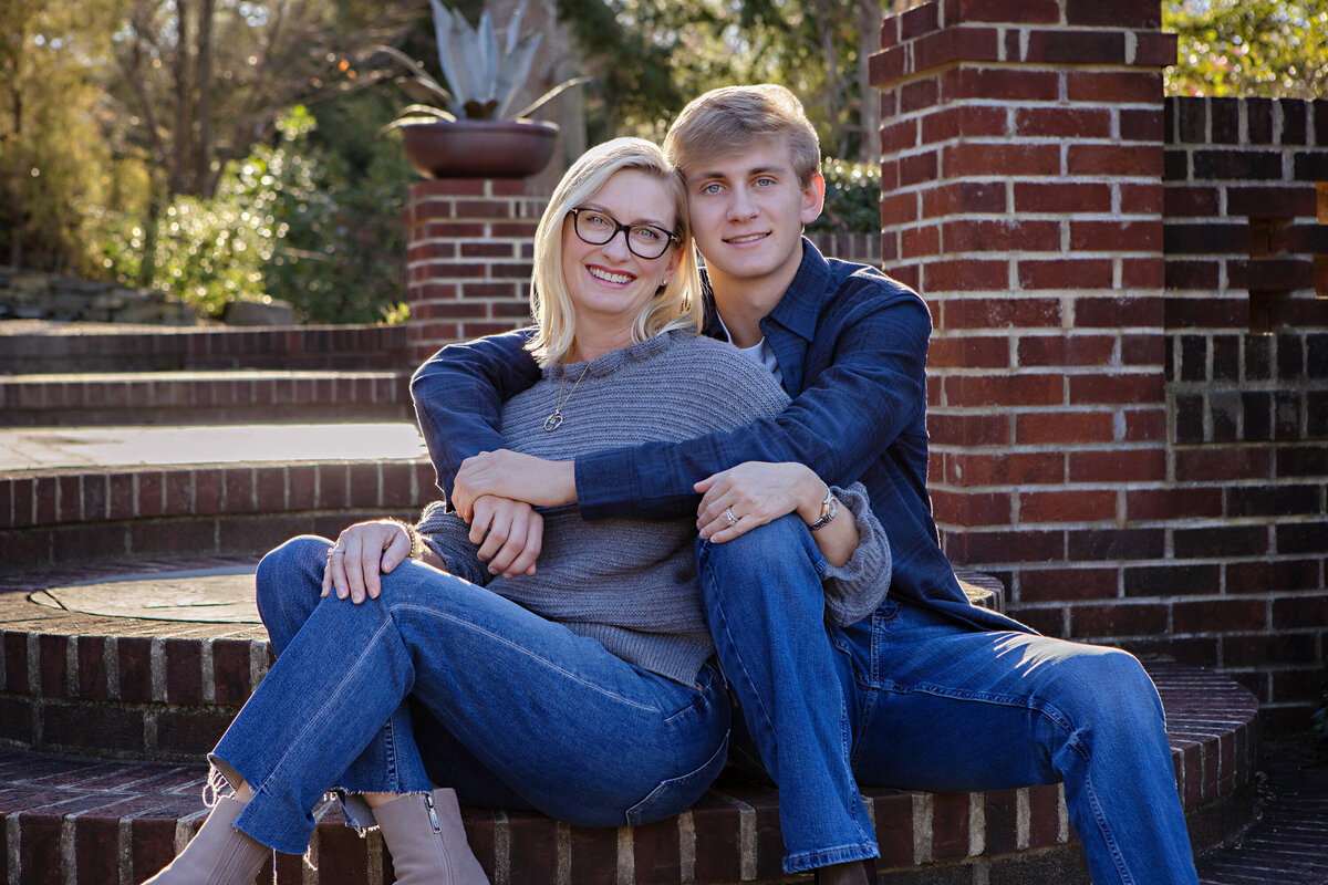 Affectionate fall moment of mom and son on brick steps surrounded by colorful foliage at UNCC Botanical Garden