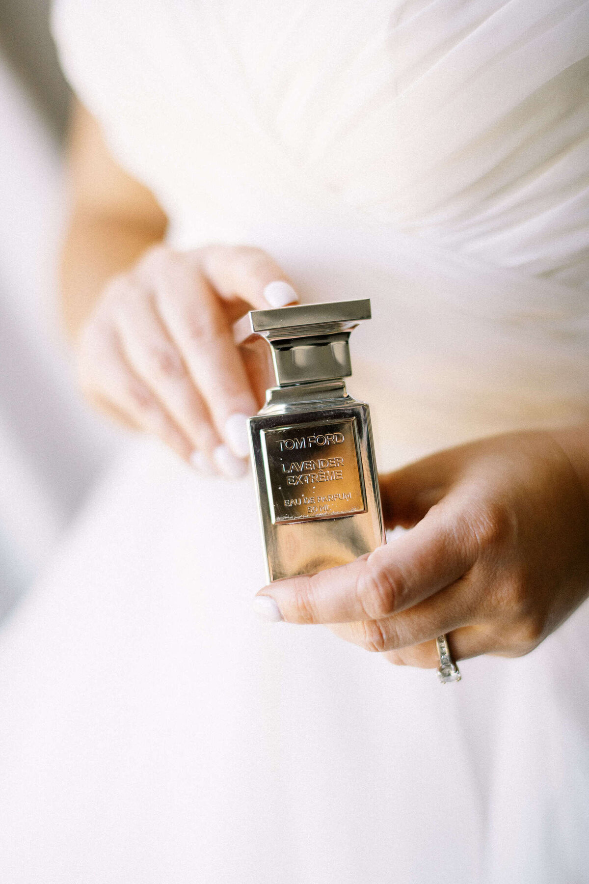 Bride holds up Tom Ford wedding perfume bottle