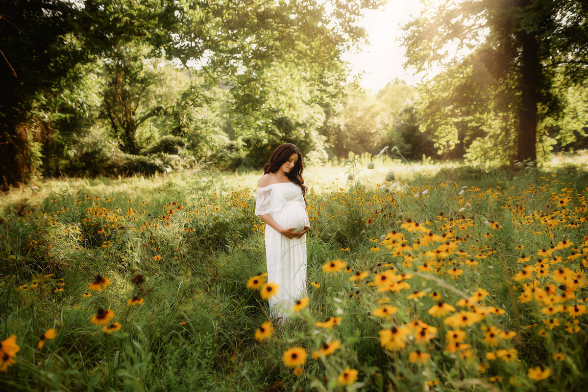 Pregnant woman poses for Maternity Photos in a flower field at Biltmore Estate in Asheville. NC.