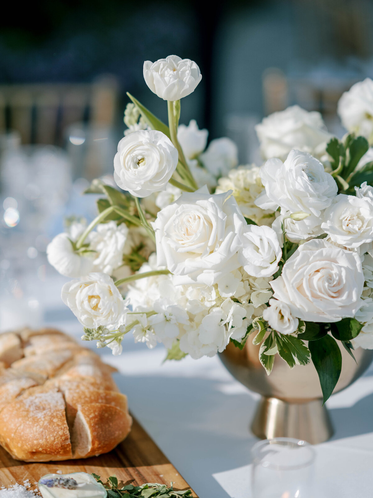 This elegant white bouquet sits in a gold vessel next to hour d'ouvres