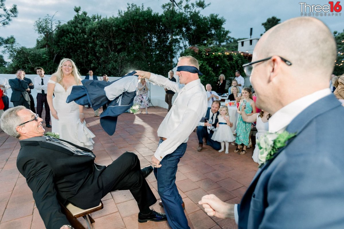 Blindfolded Groom removes jacket for Garter Belt removal on his Father in Law!