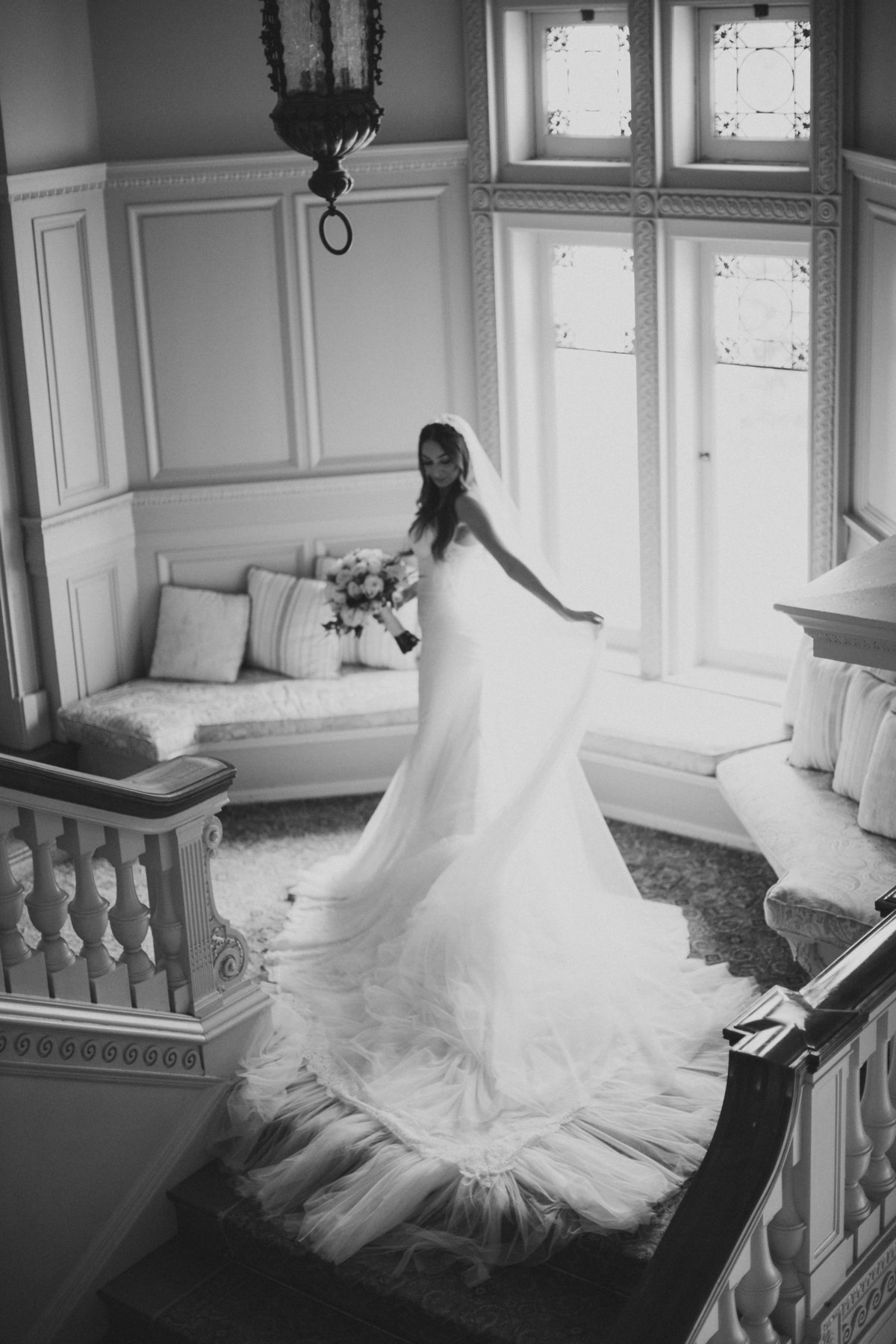 bride moving veil and standing in front of bright window during bridals