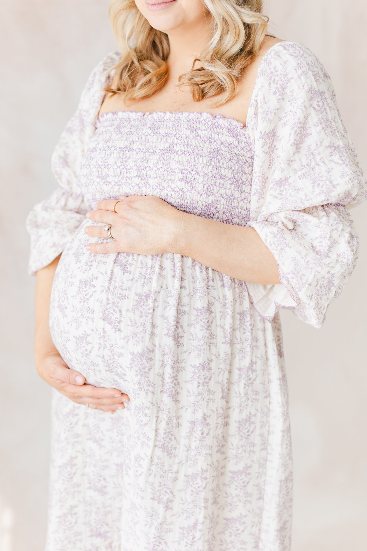 A pregnant mother holding her pregnant belly in front of a hand-painted canvas backdrop by washington dc maternity photographer