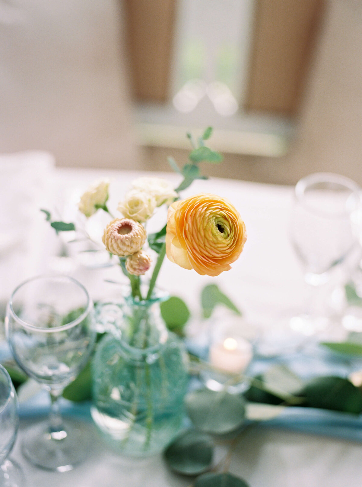 Ivory and peach wedding flowers in small glass on wedding reception table