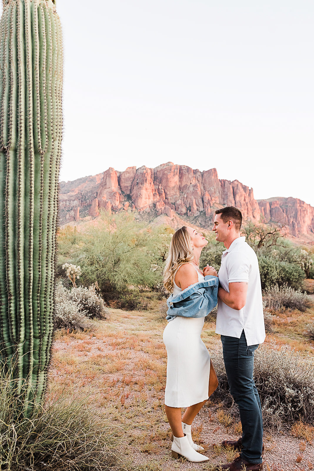 couple kissing in front os superstition mountains next to cactus