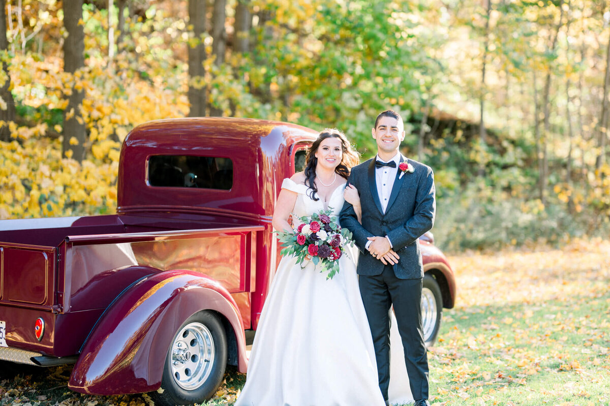 Bride and groom take wedding portraits in front of vintage red truck