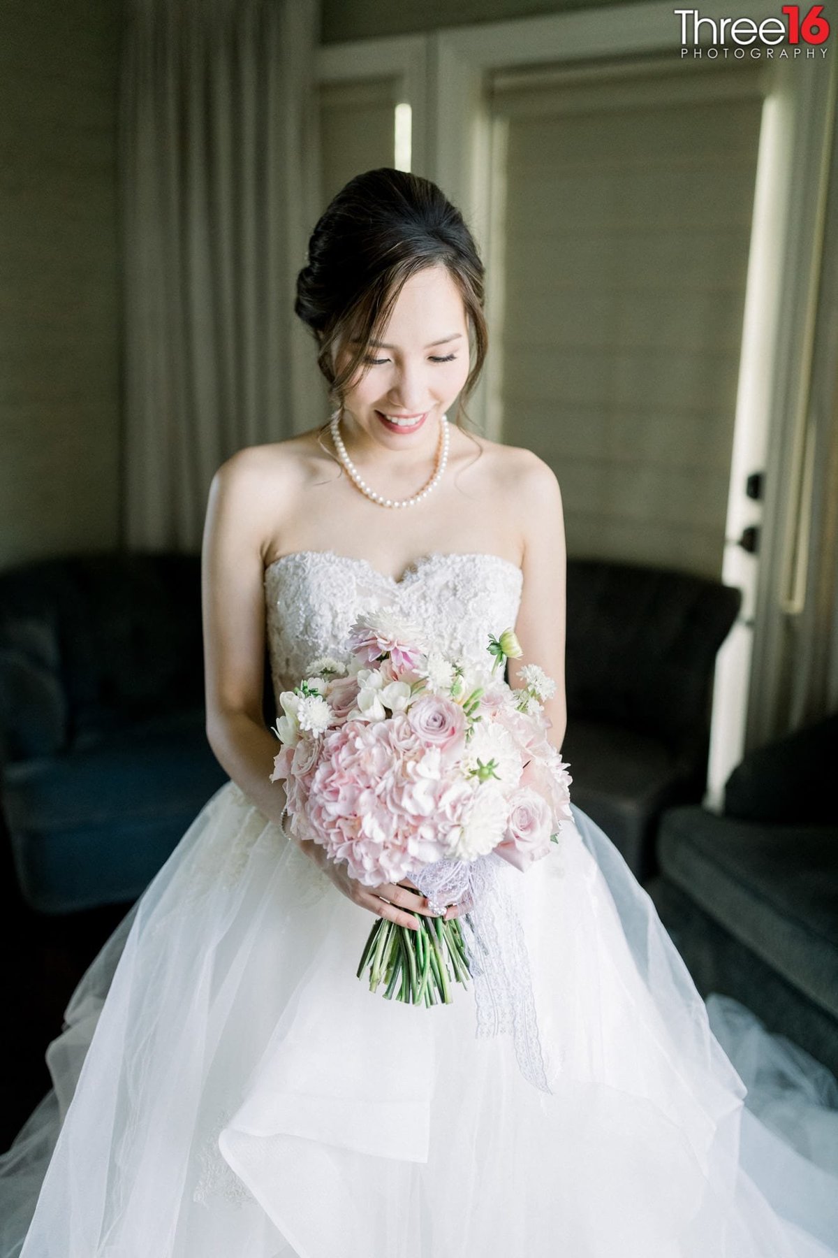 Bride poses in her wedding dress and bouquet in the dressing room prior to the start of the wedding ceremony
