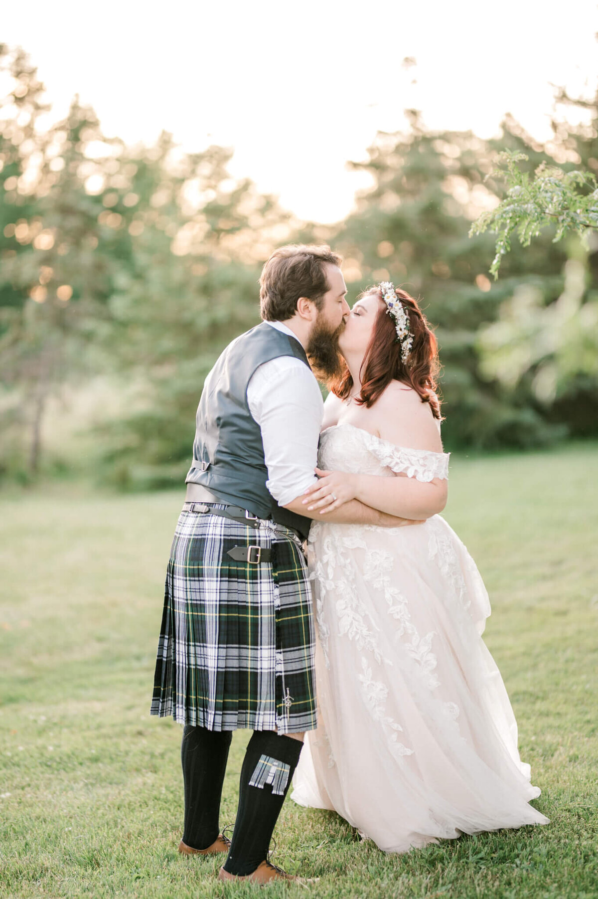 Bride and groom kissing with the groom wearing a kilt