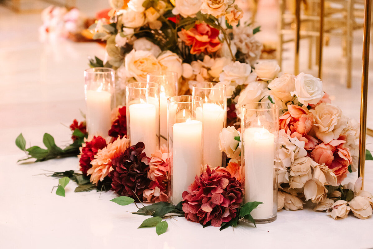 Close up of pink florals and tall white candles at wedding ceremony.