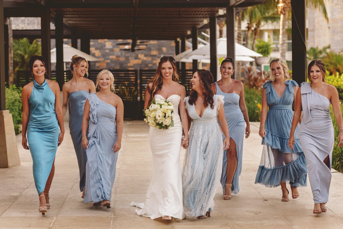 Bride walking down path holding hands with maid of honour at wedding in Cancun