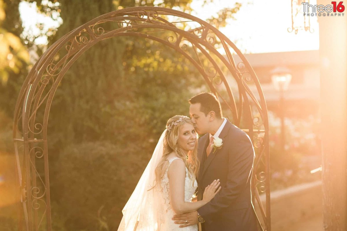 Bride receives a kiss on her head by her new Groom before the sunset