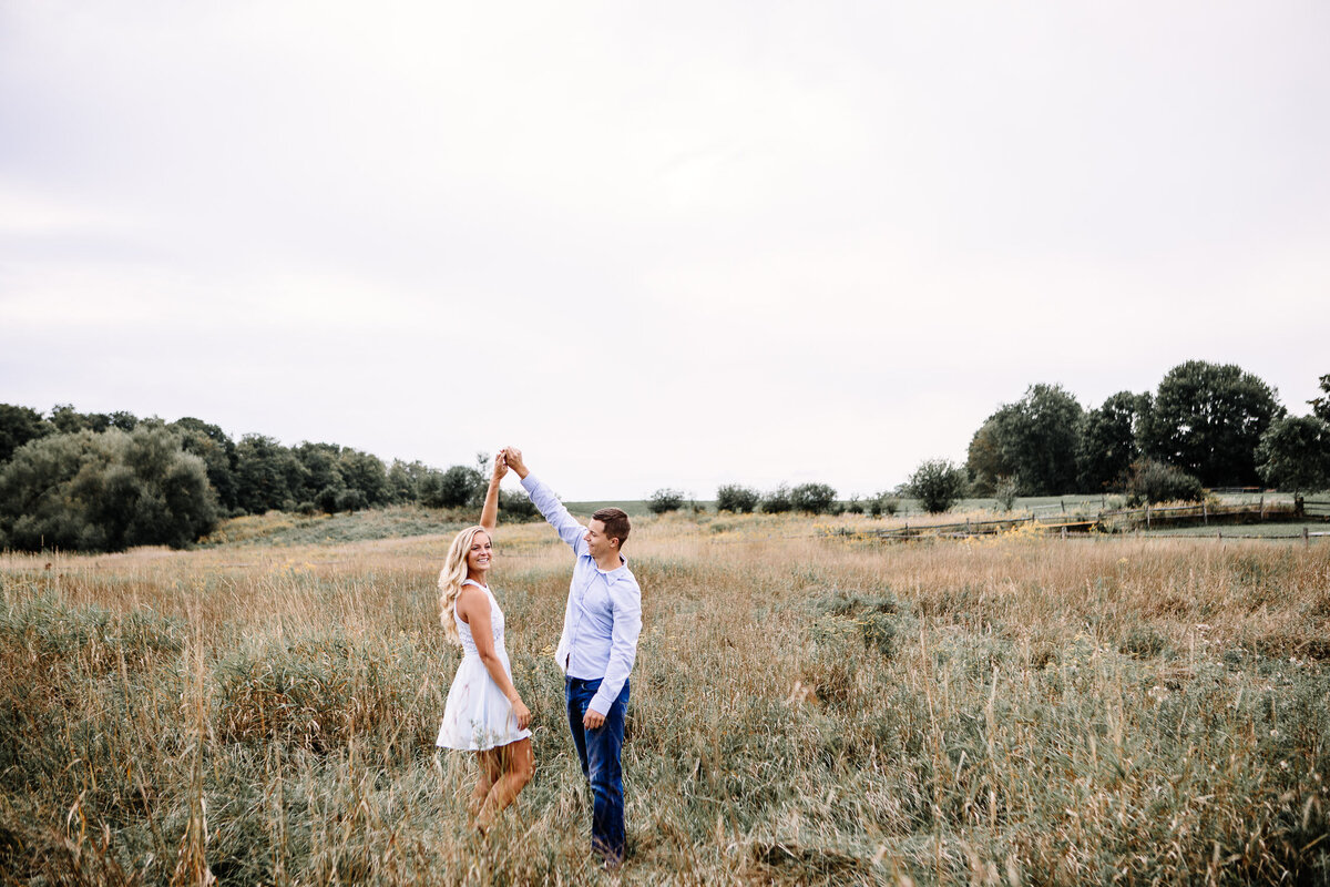 Engaged couple dancing in field in Buffalo, New York