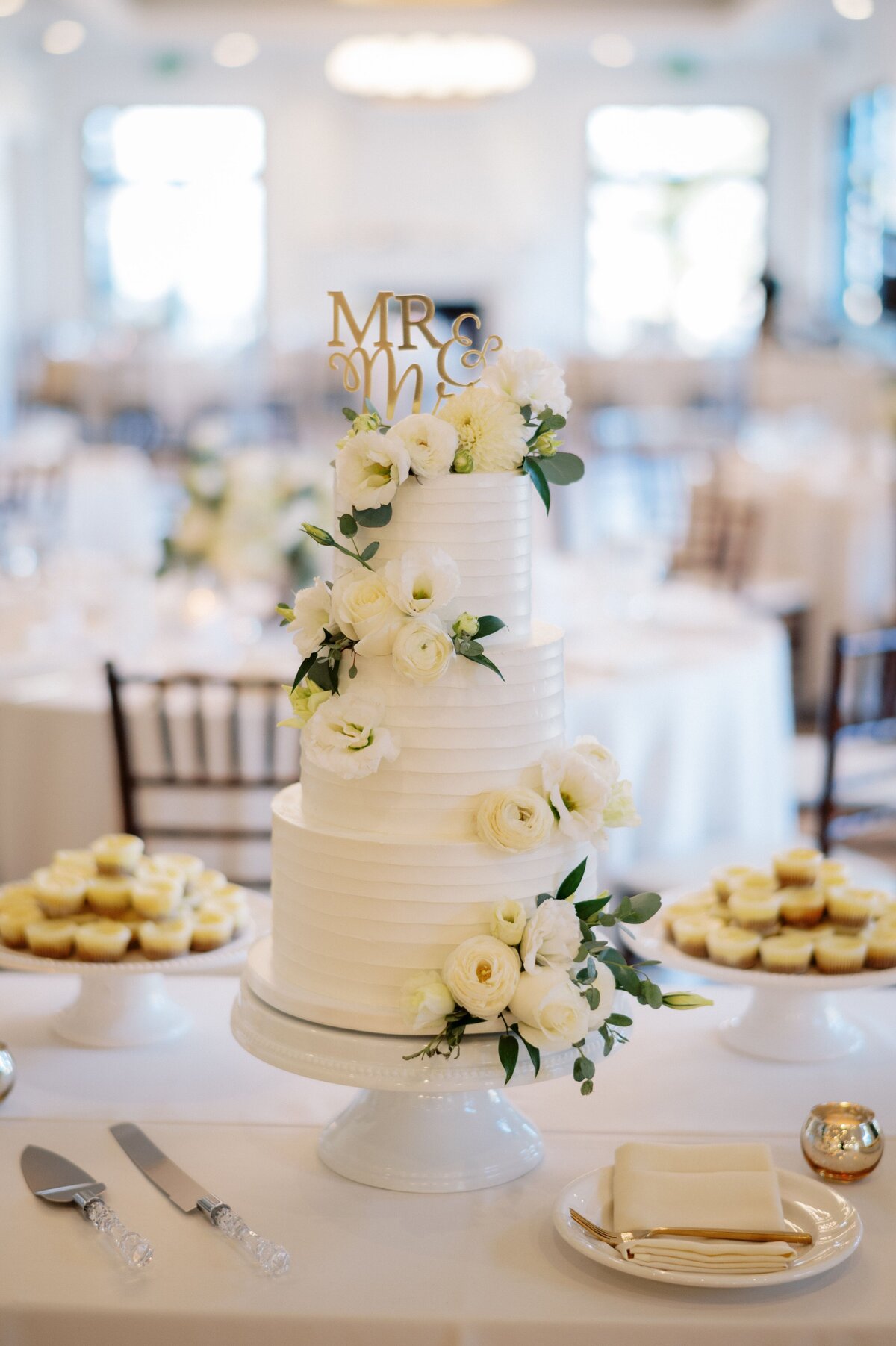A white wedding cake with white flowers adding elegance.