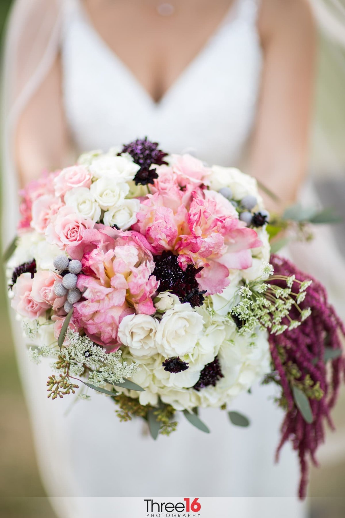 Bride holds out her bouquet of flowers at the wedding photographer