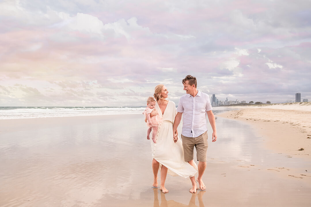 older couple on the beach having family photos taken with pink sunset backdrop in Brisbane.