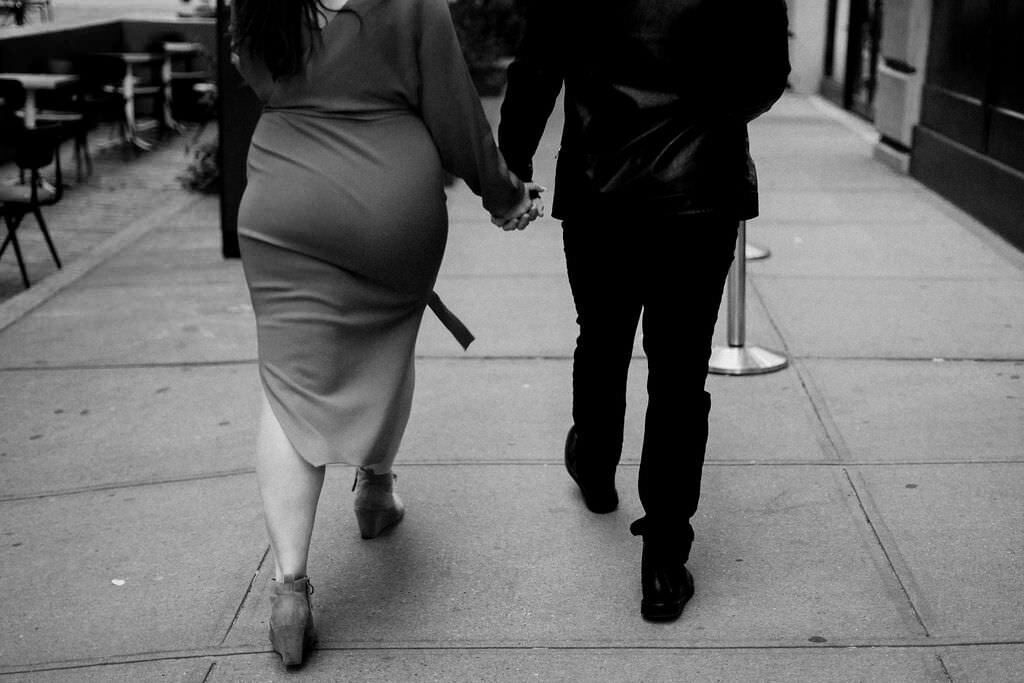 black and white photo from behind of a couple walking down a city sidewalk