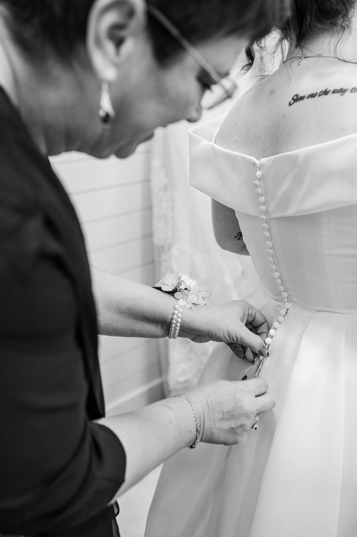 The mother of the bride zipping up the dress of her daughter on her wedding day enjoying their Raleigh wedding photography session by JoLynn Photography