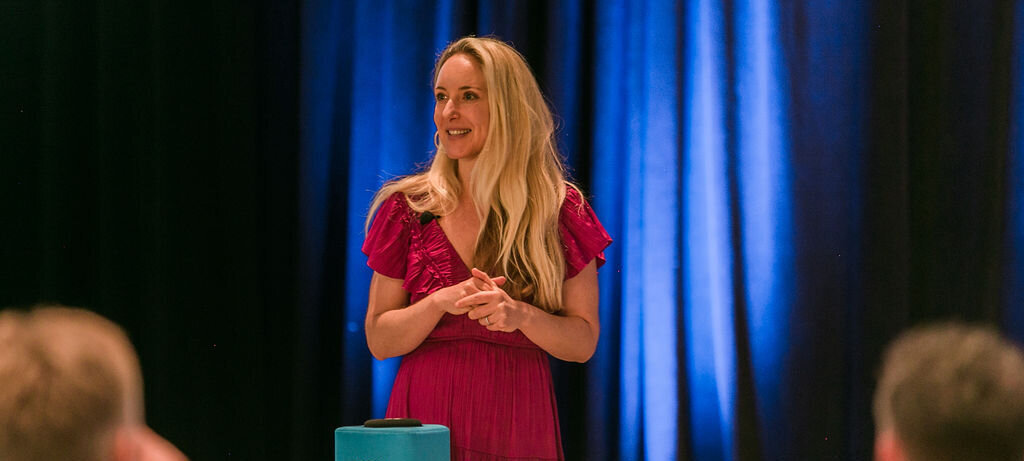 Dr. Diana Hill, ACT Psychologist Leadership Coach, speaking in a red dress with a blue curtain in the background