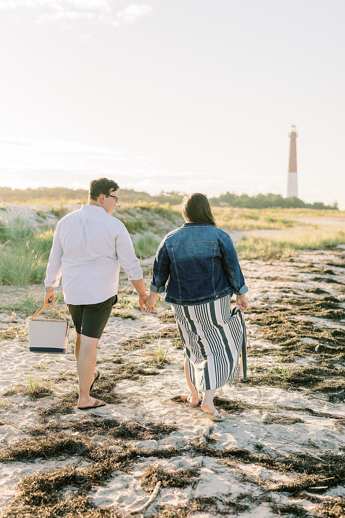 engaged couple walking near a lighthouse