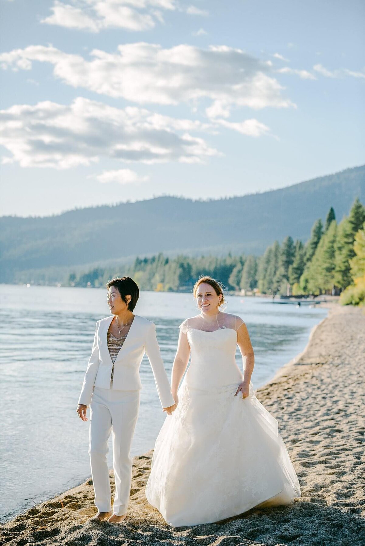 two brides walking on beach at Hyatt tahoe in Incline Village, NV. One bride has a white pant suit.