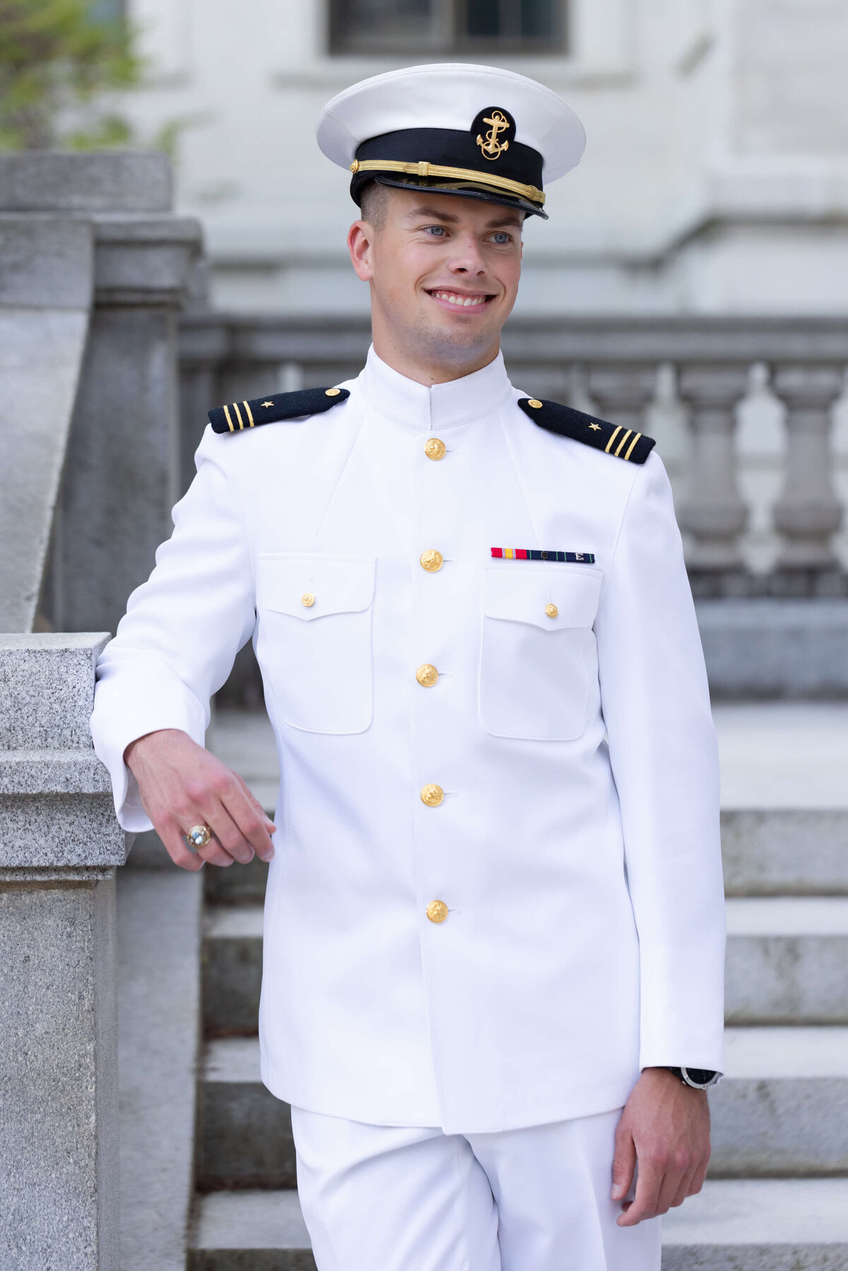 Naval Officer smiles for a senior portrait by Kelly Eskelsen outside of Mahan Hall at the Naval Academy in Annapolis, Maryland.