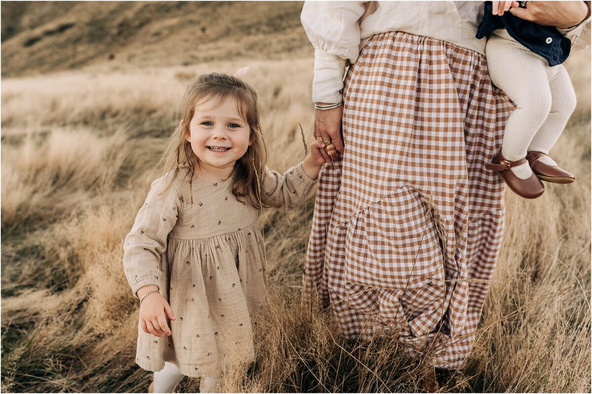 girl holding mum hand long dry grass hilltop family photos christchurch nz neutral colours
