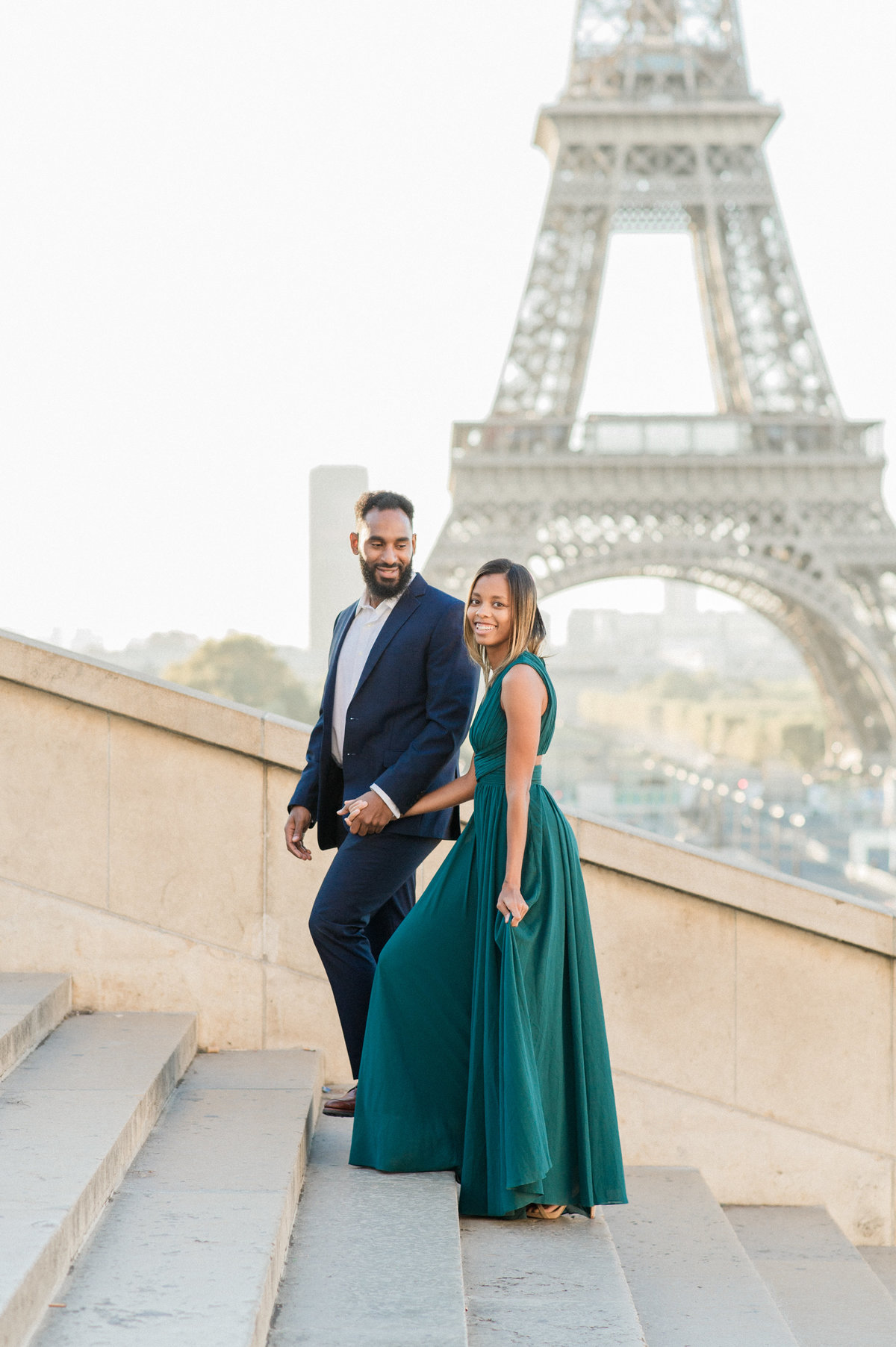 engaged couple walking up stairs at trocadero with eiffel tower in background