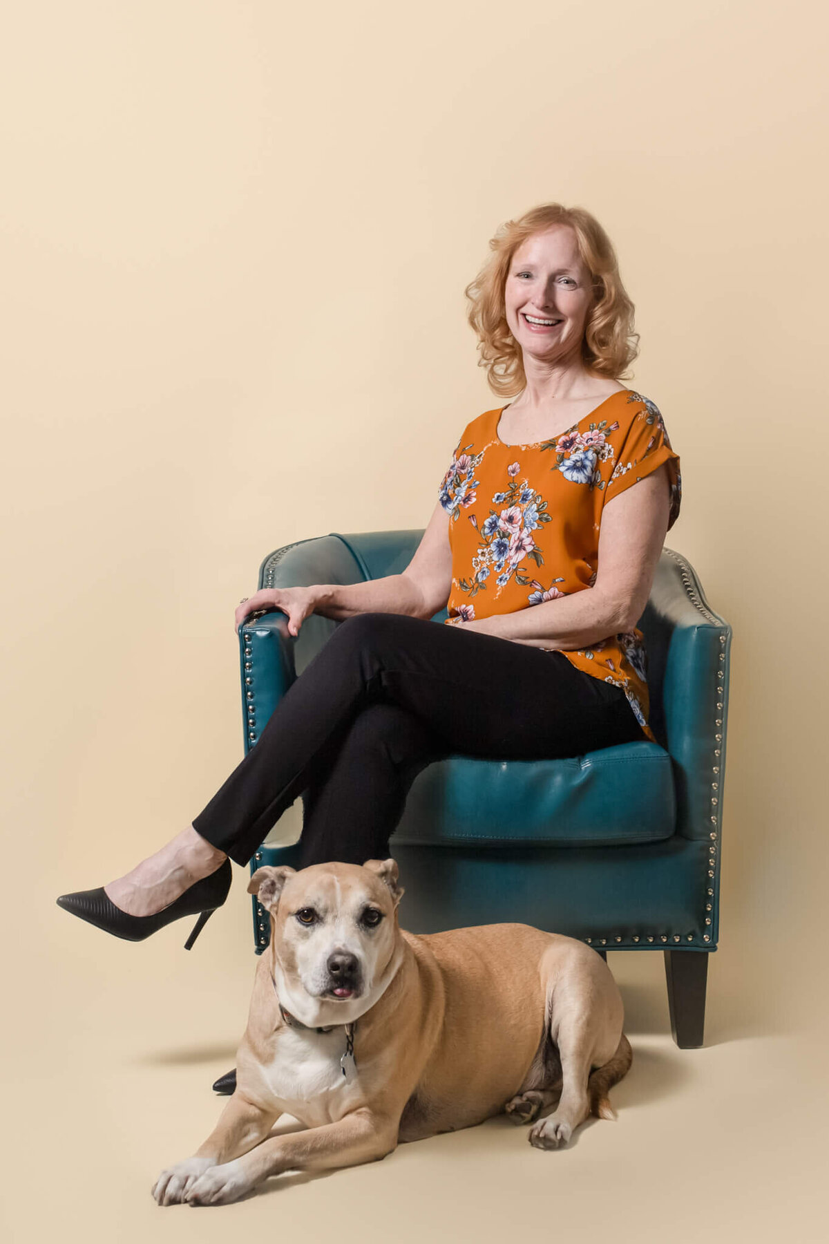 Senior end of life tan dog with his Human Mom sitting in a blue chair wearing an orange floral shirt