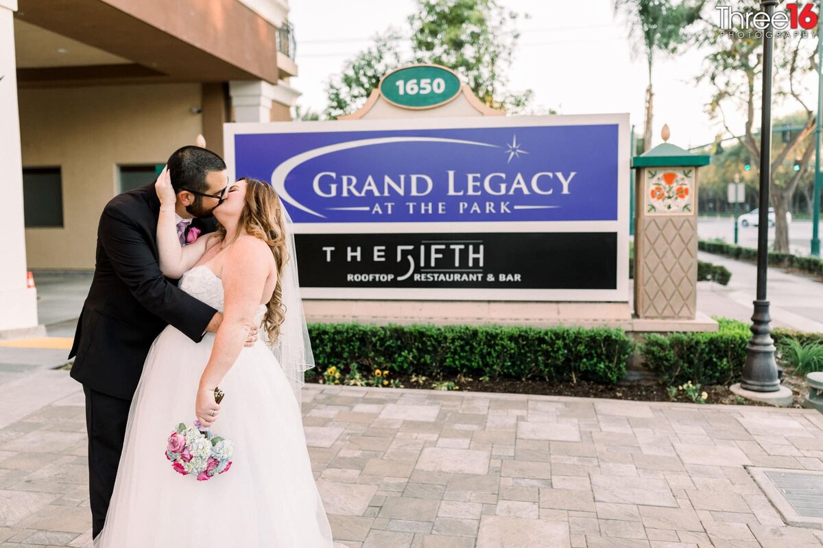 Bride and Groom share a romantic kiss in front of The FIFTH Rooftop Restaurant & Bar signage