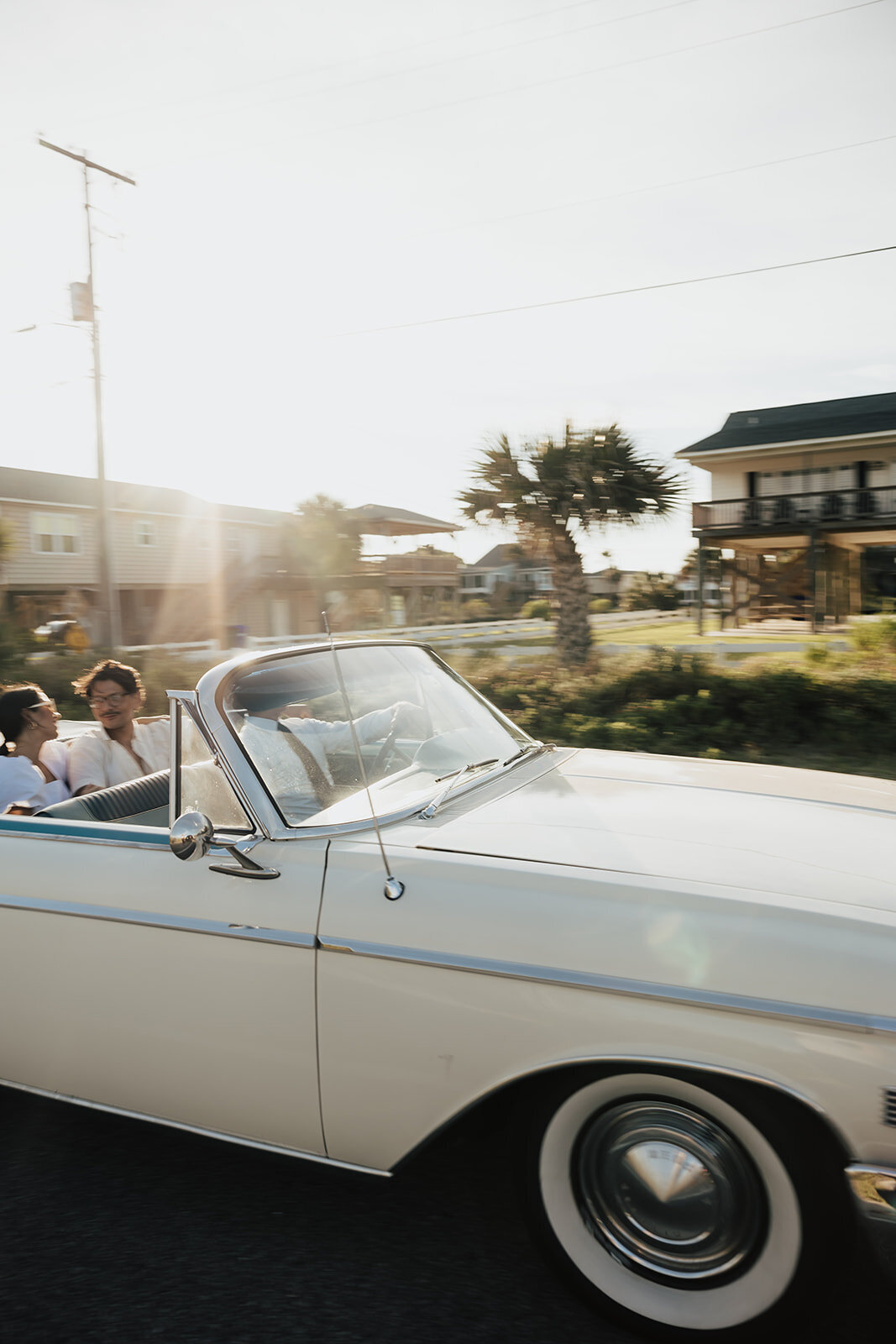 1962 MERCURY MONTEREY with cheuffeur driving on Folly BEach road with couple sitting in back. Palm tree and beach house in the background