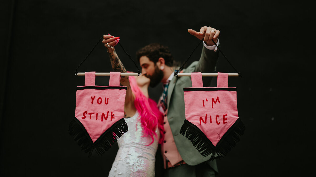 Alternative bride and groom hold up custom wedding banners at their Manchester wedding.