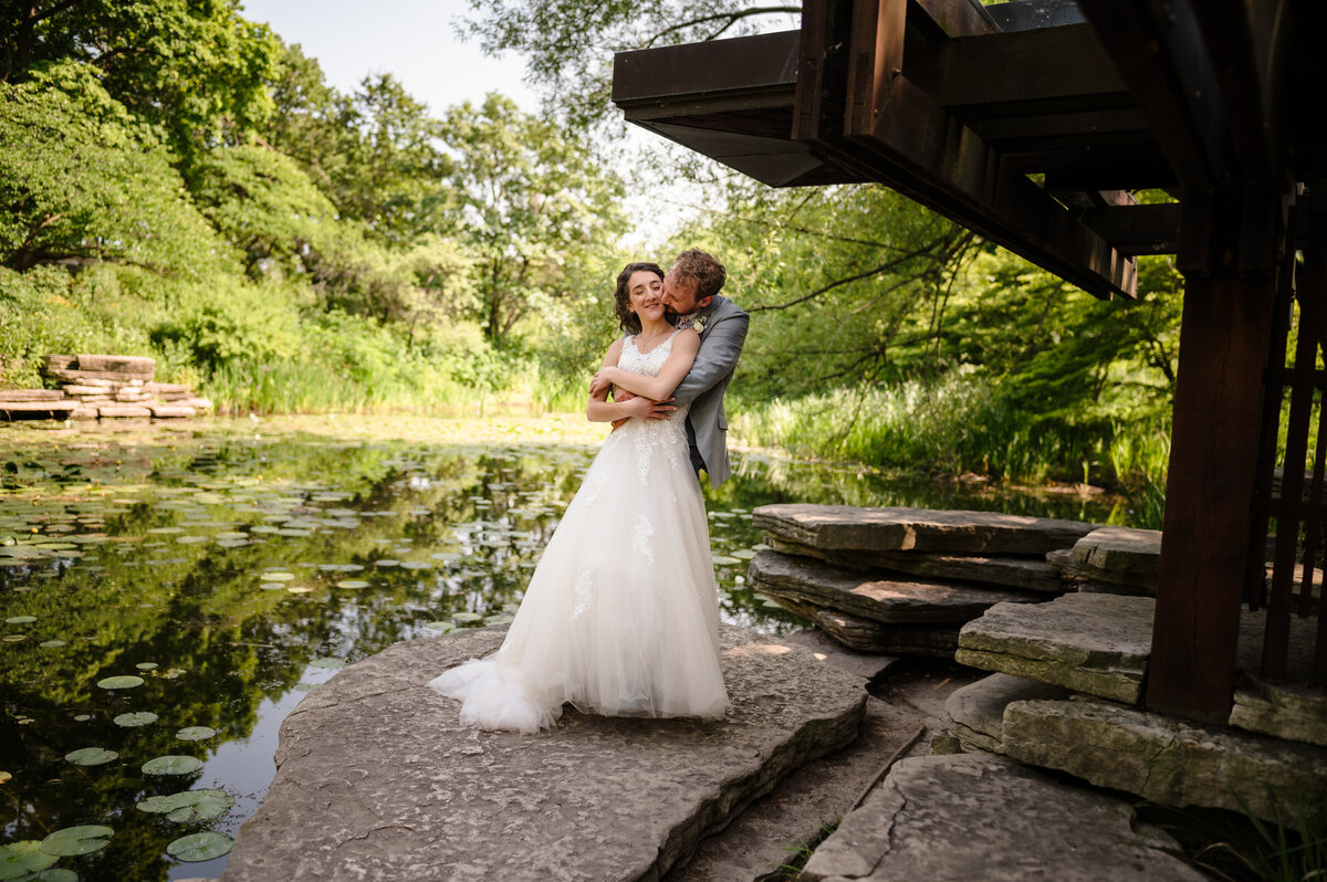 Bride and g room embrace at Alfred Caldwell Lily Pool