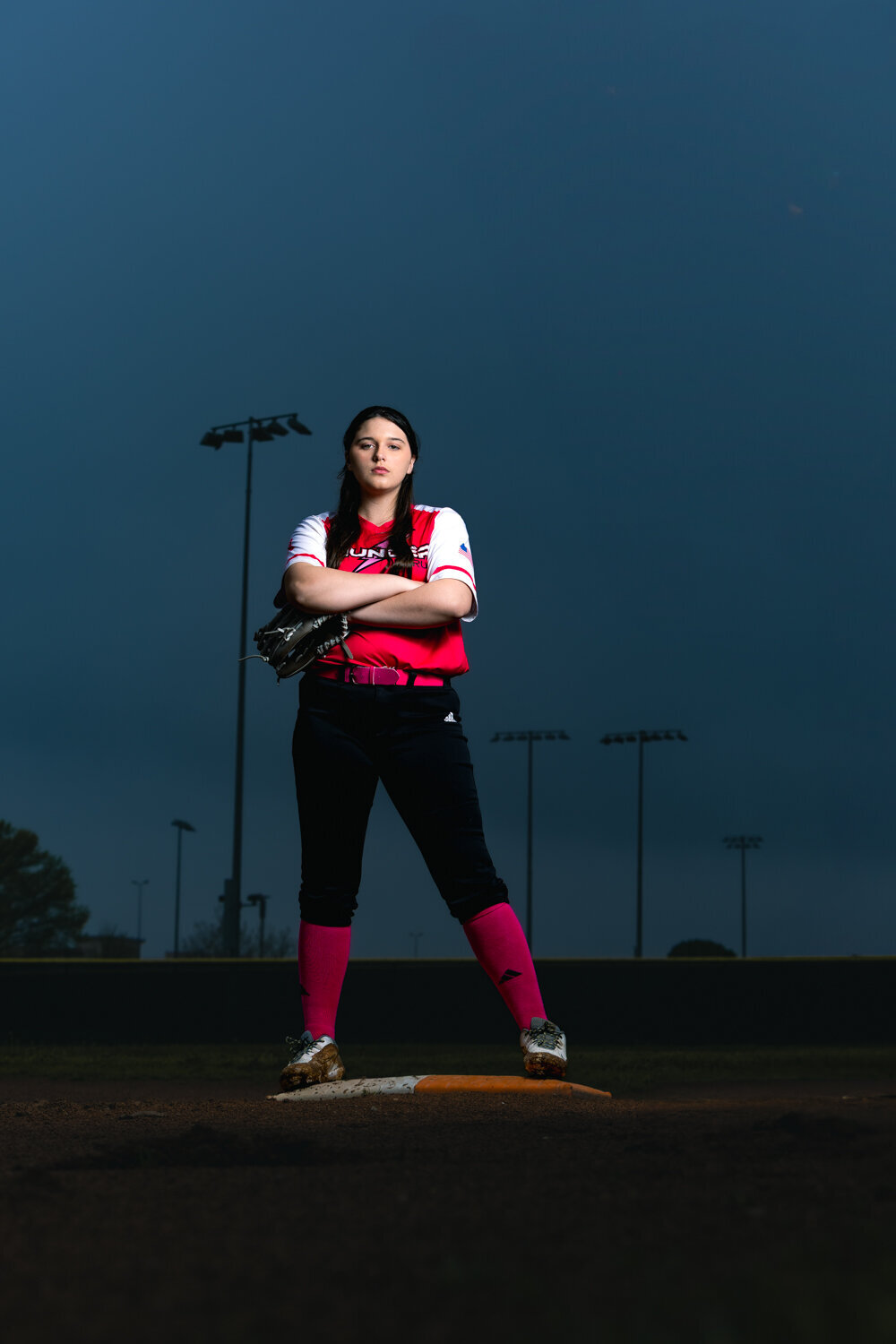 senior athlete portrait in Lansing Softball field with moody lighting and creative sports photography.