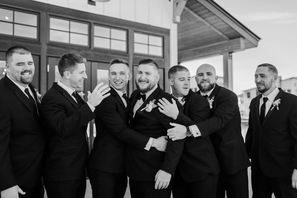 Black and white candid shot with groomsmen laughing
