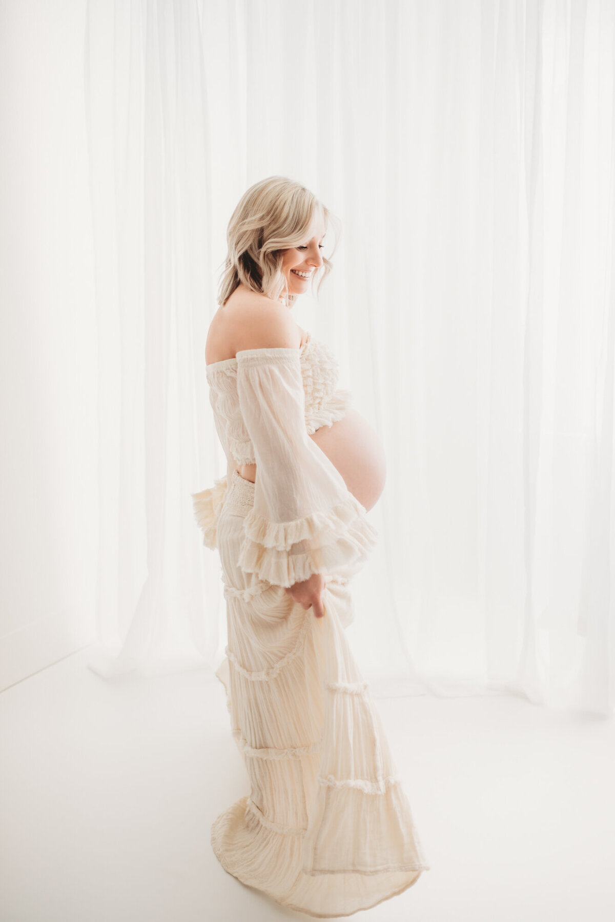 woman holding boho dress and swishing back and forth in boho dress with bare pregnant belly