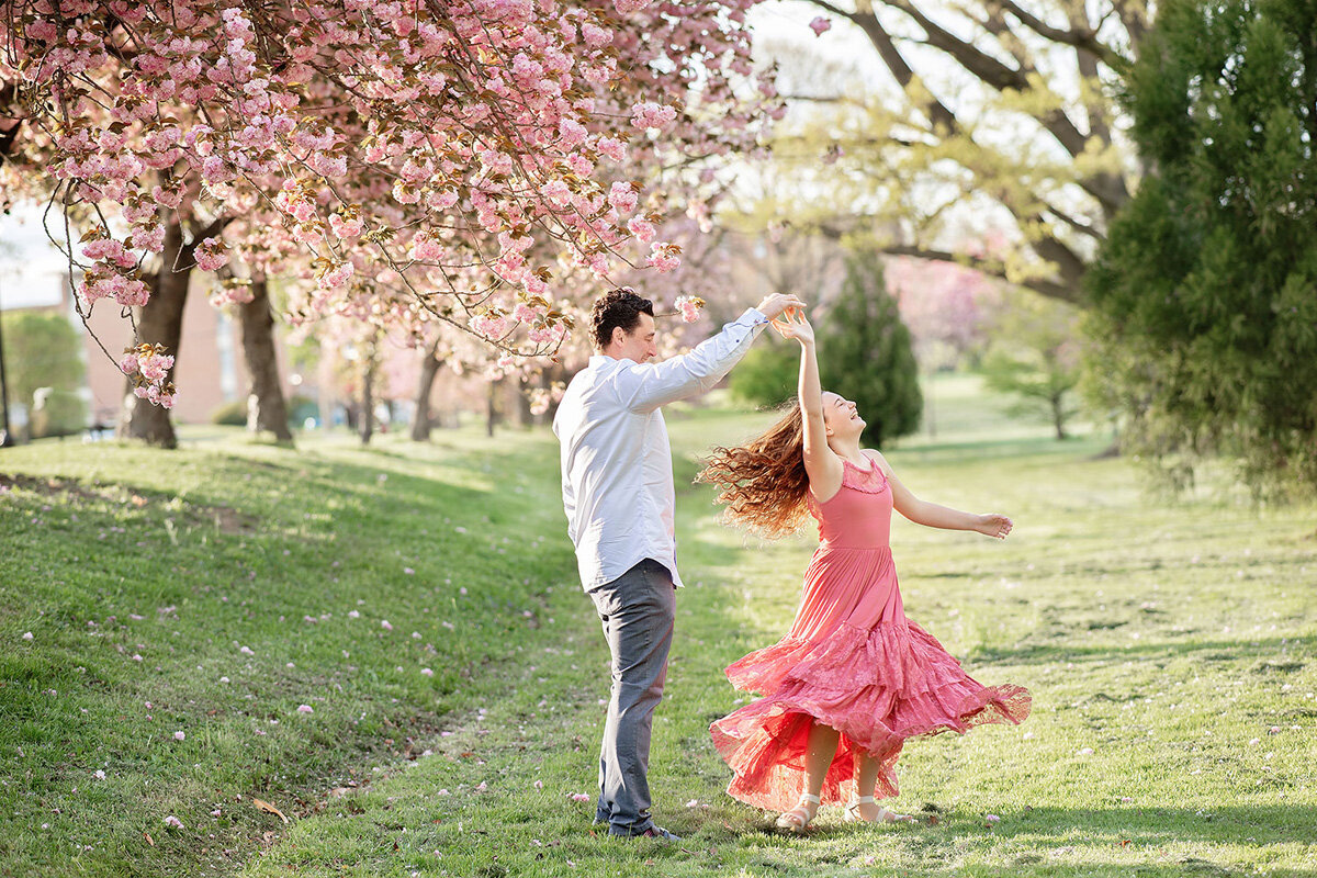 Family session with family dancing outside surrounding cherry blossoms