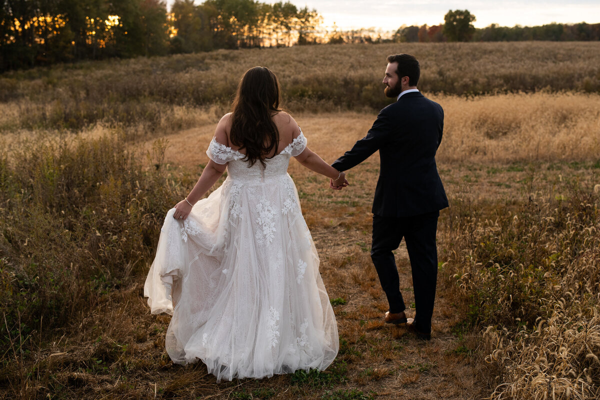 Bride and groom walk into the field behind Magnolia Hill Farm