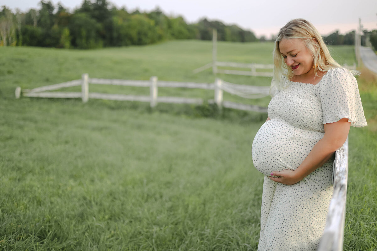 Mother holding her pregnant belly at farm in NH Maternity Photography session with Kathleen Jablonski Photography